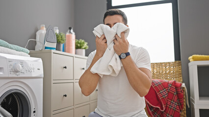 Wall Mural - Young hispanic man smelling clothes at laundry room