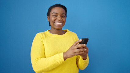 Poster - African american woman using smartphone smiling over isolated blue background