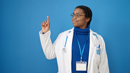 Canvas Print - African american woman doctor smiling pointing to the side over isolated blue background