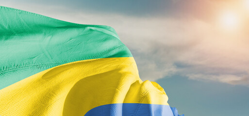 Gabon  national flag cloth fabric waving on beautiful sky Background.