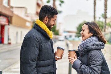 Wall Mural - Man and woman couple smiling confident drinking coffee at street