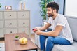 © Krakenimages.com - Young arab man playing video game sitting on sofa at home