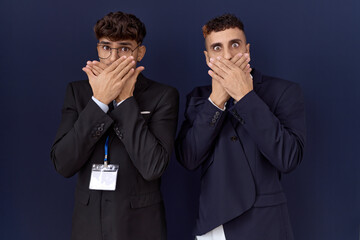 Wall Mural - Two hispanic business men wearing business clothes shocked covering mouth with hands for mistake. secret concept.