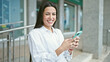 © Krakenimages.com - Young beautiful hispanic woman using smartphone smiling at street