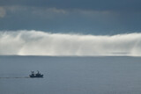 Fototapeta Tęcza - A bank of fog on the sea with a boat in the foreground