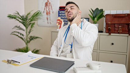 Wall Mural - Young hispanic man doctor sitting on table stressed at clinic