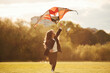© standret - Beautiful sunlight. Happy little girl is playing with kite on the summer field