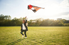 Photo In Motion. Happy Little Girl Is Playing With Kite On The Summer Field
