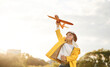 © standret - In yellow colored jacket. Little boy is playing with toy plane on the summer field