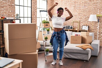 African american woman listening to music and dancing at new home