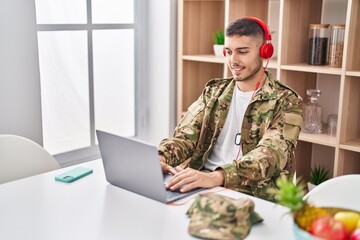 Wall Mural - Young hispanic man army soldier using laptop and headphones at home