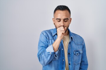 Canvas Print - Young hispanic man standing over isolated background feeling unwell and coughing as symptom for cold or bronchitis. health care concept.