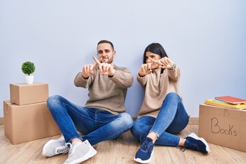 Poster - Young couple moving to a new home rejection expression crossing fingers doing negative sign