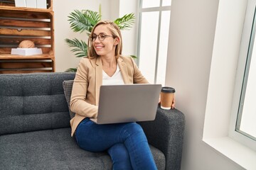 Wall Mural - Young blonde woman psychologist using laptop drinking coffee at psychology clinic