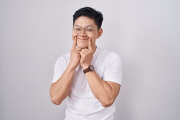 Sticker - Young asian man standing over white background smiling with open mouth, fingers pointing and forcing cheerful smile