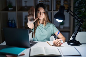 Poster - Teenager girl doing homework at home late at night doing stop sing with palm of the hand. warning expression with negative and serious gesture on the face.