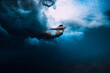Woman swim underwater with breaking wave with foam in transparent ocean.