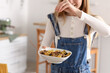 Young woman with spicing tasty pasta in kitchen, closeup