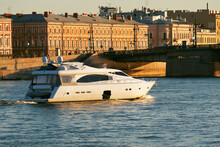 A White Motor Yacht Sails At Sunset On The River Of A European City. A Passenger Boat Floats On The Water On A Summer Evening, Against The Backdrop Of Beautiful Architecture.