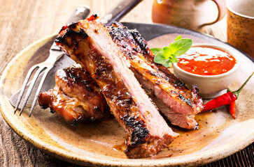 Wall Mural - Barbecue veal spare ribs sliced with hot honey chili marinade served as close-up on a rustic design plate