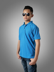 Sticker - Young Asian teenage boy wearing blue collared shirt and sunglasses standing with hands on hip over grey background, t-shirt template