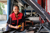 Fototapeta Dziecięca - One Black female professional automotive mechanical worker checks an EV car battery and hybrid engine at a maintenance garage, expert electric vehicle service, and fixing occupations auto industry.