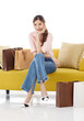 © Bangkok Click Studio - Portrait isolated cutout studio shot of Asian cheerful female client customer shopper in casual outfit sitting on cozy sofa take break buying stuff in paper shopping bags in store on white background