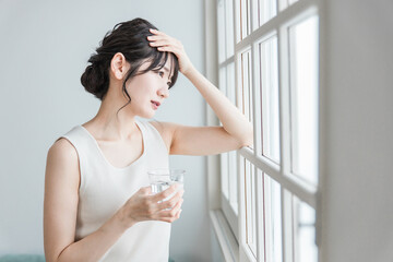 朝、体調不良・発熱・偏頭痛に悩むアジア人の女性
