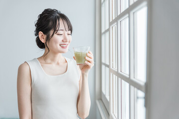 Poster - 家でグリーンスムージーを飲む笑顔のアジア人女性
