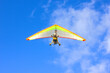 On a clear sunny day, a hang glider flies high in the sky.