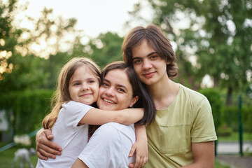 Young adult caucasian beautiful mother enjoy having fun with two cute children outdoors on warm summer day. Family nature outdoor recreation lifestyle. High quality photo