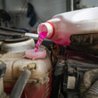 The process of pouring antifreeze into the expansion tank of a car, a planned replacement of the engine coolant, close-up