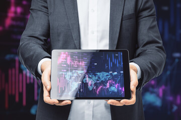 Poster - Close up of businessman hand holding tablet with downward purple forex chart on dark background. Crisis and recession concept.