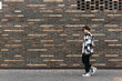 © Evgeny - young man walks down the street in front of a brick wall