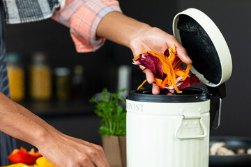 Midsection of biracial man wearing apron preparing meal, composting vegetable waste in kitchen