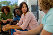 Group of diverse people sitting on sofa and talking in group therapy session
