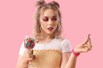 Poster - Young woman with glass of candies on pink background