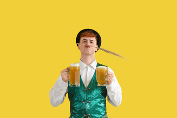 Young man in traditional German clothes with dry reeds and beer on yellow background