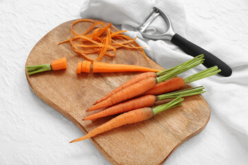 Wooden board with fresh carrots and slices on white background