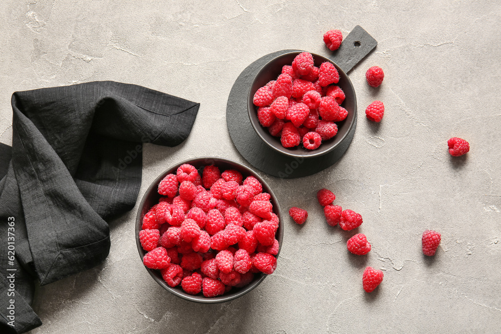 Bowls with fresh raspberries on grey table
