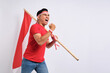 Excited young Asian man celebrate Indonesian independence day on 17 August by holding the Indonesian flag isolated over white background