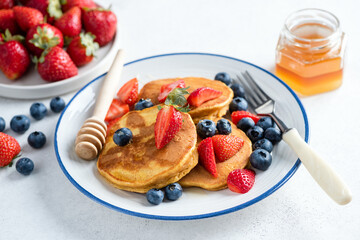 Wall Mural - Delicious gluten free corn pancakes with sweet summer berry fruits and honey, closeup view