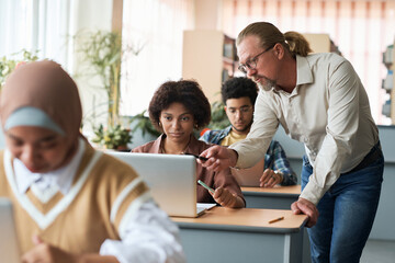 Mature teacher teaching group of foreign students during lesson in class