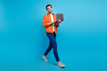 Fototapete - Full size profile portrait of positive nice man hold wireless netbook walking isolated on blue color background