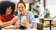 © (JLco) Julia Amaral - Two business women using a smartphone together during a coffee break