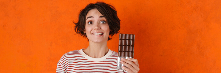 Wall Mural - Young brunette woman smiling while posing with chocolate