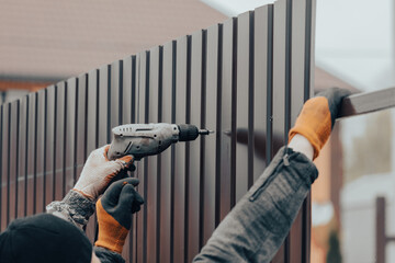 Workers install a metal profile fence