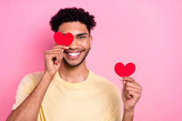 Canvas Print - Portrait of positive cheerful man afro hairstyle dressed yellow t-shirt hold red likes cover eye isolated on pink color background