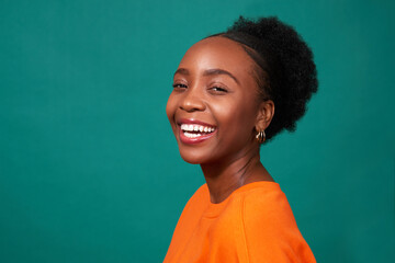 Beautiful Black woman smiles, studio teal background, fashion lifestyle portrait