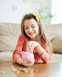 © Lumos sp - child saving money girl bank finance investment coin happy save wealth young piggy cash kid little economy financial childhood banking pig piggybank home family cute future currency
